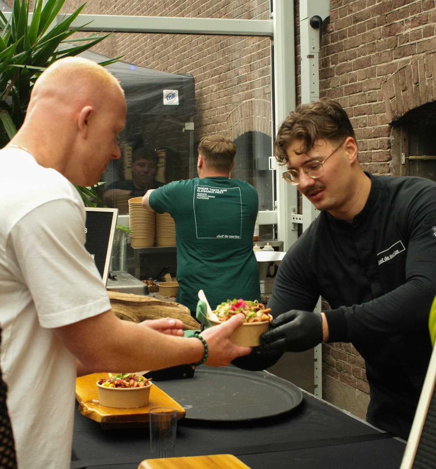 Chef handing a freshly finished bowl to a guest