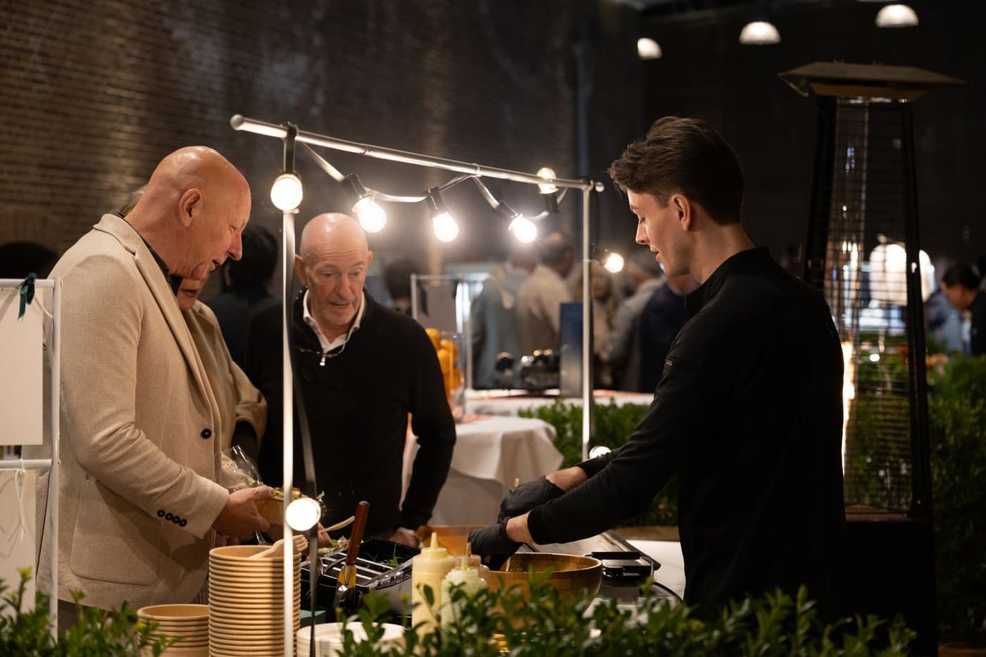 Guest being handed a dish at a foodstand during an evening event